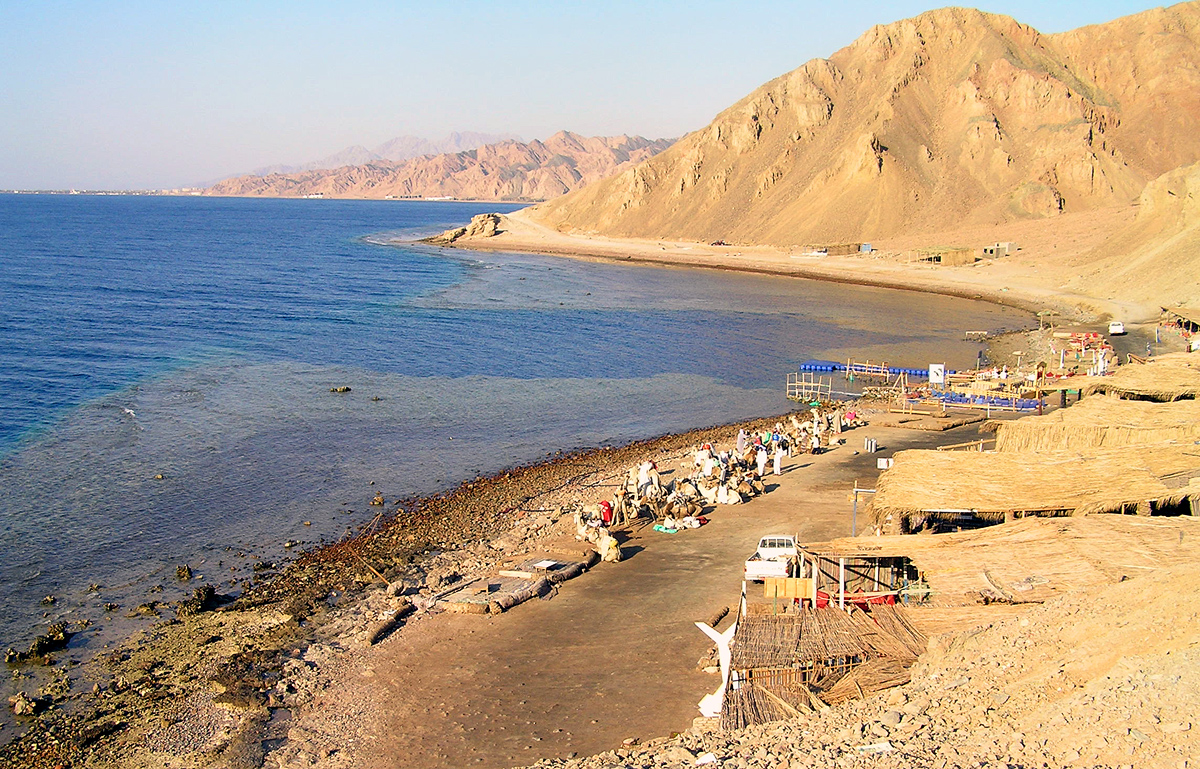 Blue Hole shoreline near Dahab, with turquoise shallows and golden Sinai mountains.